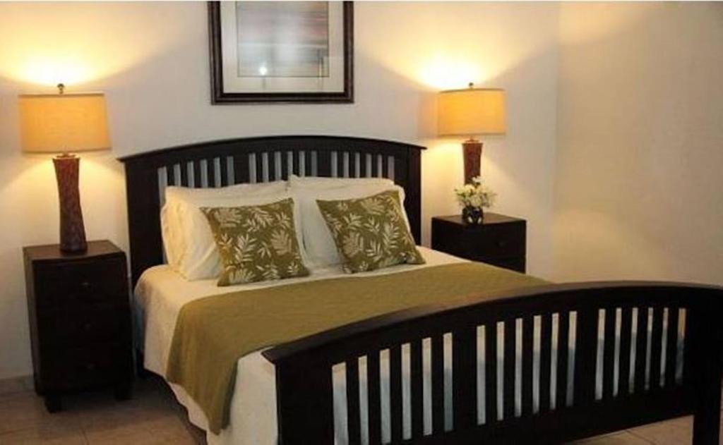 13 Best Hotels in Old San Juan, Puerto Rico 2024 11 A large bed with white and green colored sheets with bedside tables and lamp on both sides. A picture frame is hanging right above the bed. This is in the Fortaleza Suites in Old San Juan, Puerto Rico