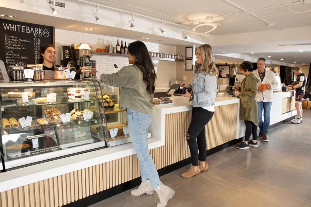 Where to Stay in Banff National Park: 18 Best Hotels (2024) 14 Five people ordering a snack on a cafe counter with pastries and coffee. This is the cafeteria of the Banff Aspen Lodge.
