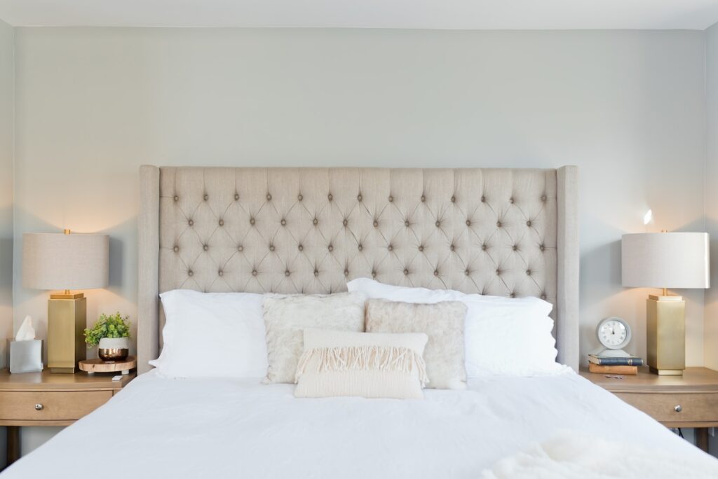 Where to Stay Near Jasper National Park: 16 Best Hotels 2 A bed with white sheets and upholstered headboard in between two bedisde tables with lamps. This is in the Jasper Inn & Suites in Jasper National Park.