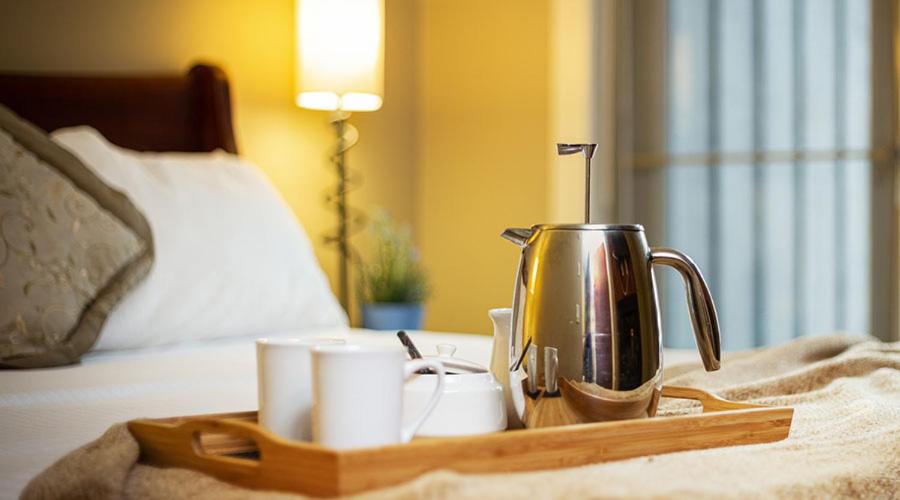 Where to Stay in Banff National Park: 18 Best Hotels (2024) 20 A focused photo of a teapot with a milk frother and two white porcelain mugs above a wooden tray. This tea'coffee set is placed above a bed. This complimentary set is from the Solara Resort in Canomore near Banff National Park