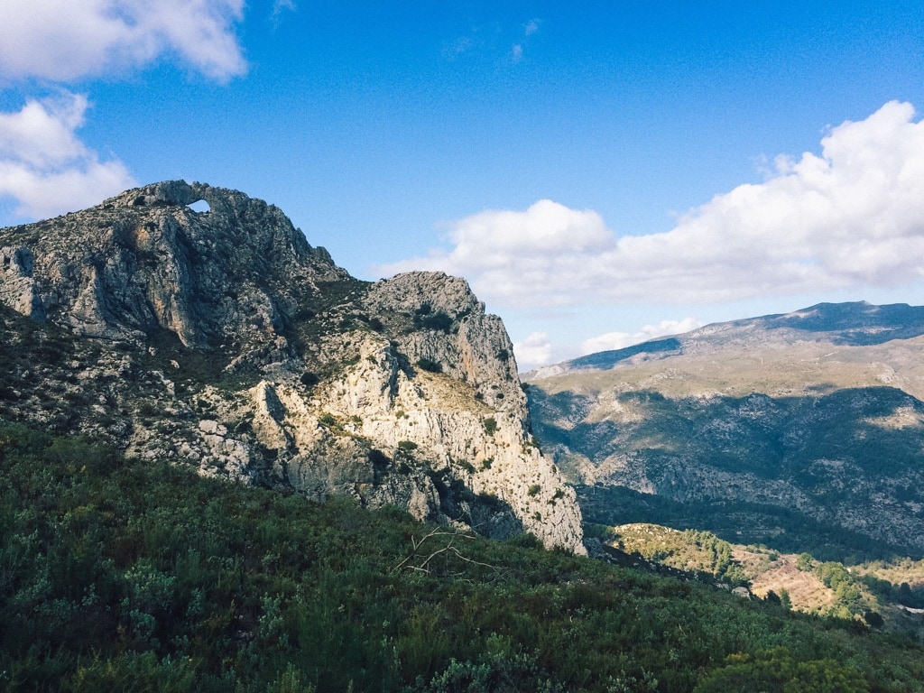 27 Pros and Cons of Living in Spain in 2024 5 View of Hole in the Rock in Benisiva Spain, where Nina lived, where you can see the hole with blue sky through it on the mountain.