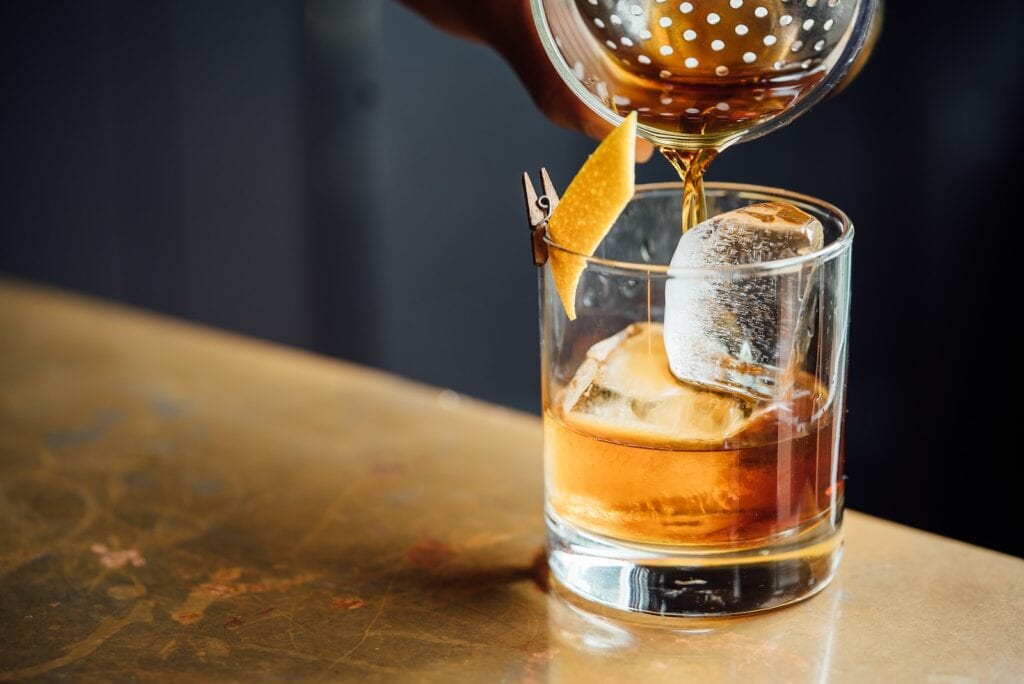 27 Pros and Cons of Living in Tennessee in 2024 11 A person pouring a brown transluscent liquid in a clear glass. Tennesse takes pride in its smooth premium whiskeys which are famous around the world/