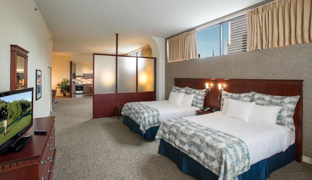 22 Best Places to Stay in Montreal Canada 2 Two beds with blue and white sheets inside a room with a small flat screen TV. This is in Le Square Phillips, one of the best places to stay in Montreal Canada.