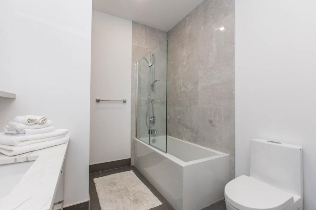 22 Best Places to Stay in Montreal Canada 14 A bathroom with a white ceramic bathtub, a shower, and a toilet near the well. A sink with white towels placed on top can also be seen. This is in Lofts du Parc Lahaie one of the best places to stay in Montreal Canada.