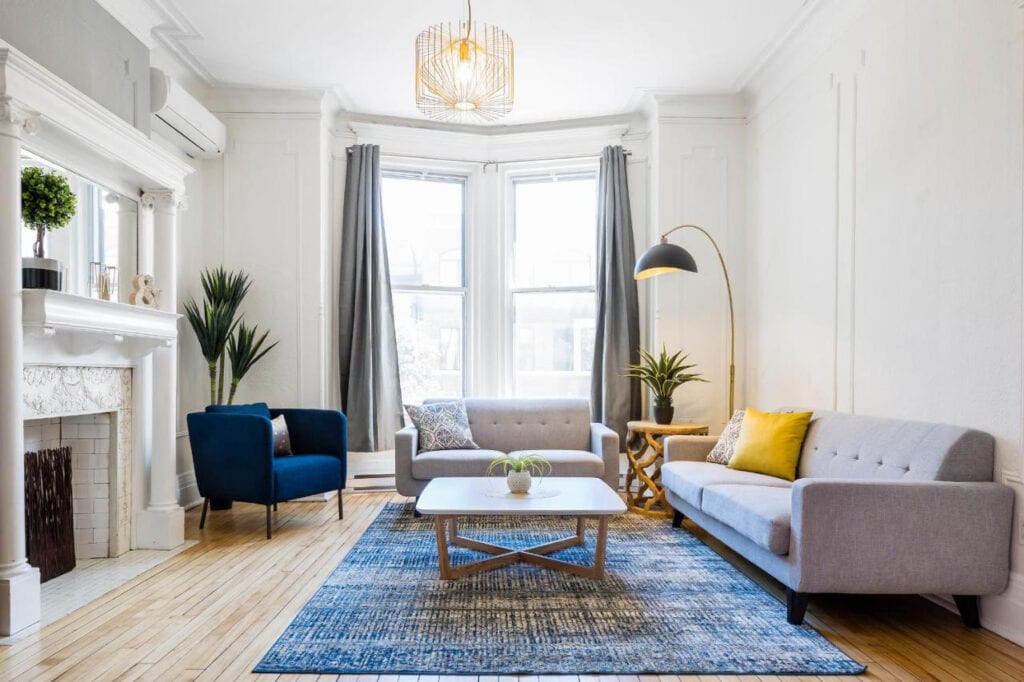 22 Best Places to Stay in Montreal Canada 15 A living room with white walls that has two gray sofa and a single blue upholstered chair. There is a coffee table and a fire place in front of the sofas. This room is in the Chic Laurier, one of the best places to stay in montreal Canada.