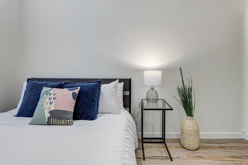 22 Best Places to Stay in Montreal Canada 17 A bedroom with white walls and wooden floors that has a bed with white sheets and a bedside table with a lamp. This is one of the rooms in the Sunny Getaway Hotel in Montreal Canada.