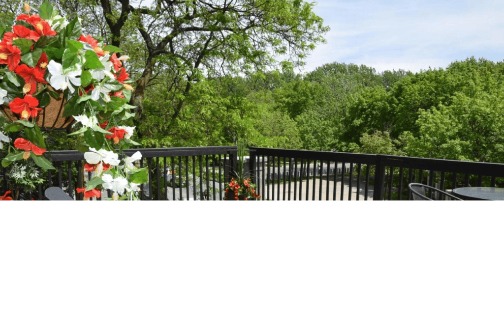 22 Best Places to Stay in Montreal Canada 12 Two sunbathing chairs on a porch with wooden flooring and black fence under a sunny sky. This is in Auberge de la Fontaine in Montreal Canada.