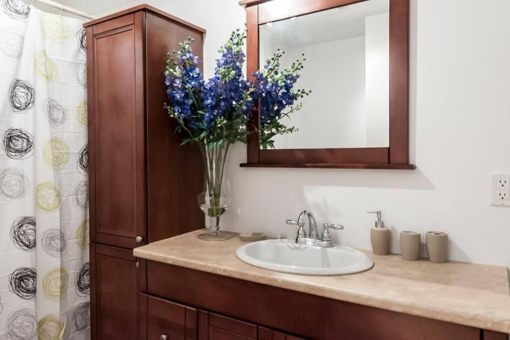 22 Best Places to Stay in Montreal Canada 11 A marble sink with a mirror above it and a vase of purple flowers placed on top. The Le Metro in Montreal, is a popular place to stay in the city.