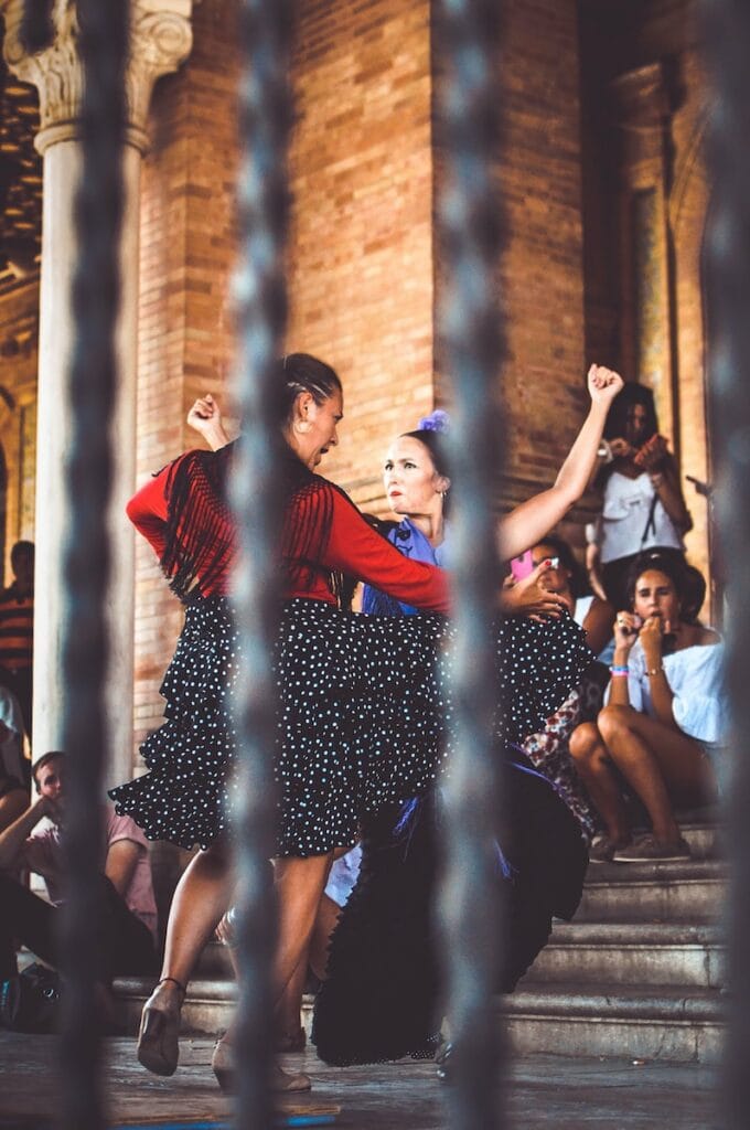 27 Pros and Cons of Living in Spain in 2024 11 two women dancing outdoors in Spain on the streets