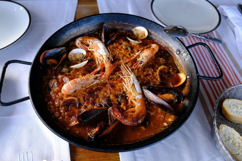 27 Pros and Cons of Living in Spain in 2024 4 cooked shrimp on top of a paella - one of the best Spanish foods, and what I lived off of in Spain