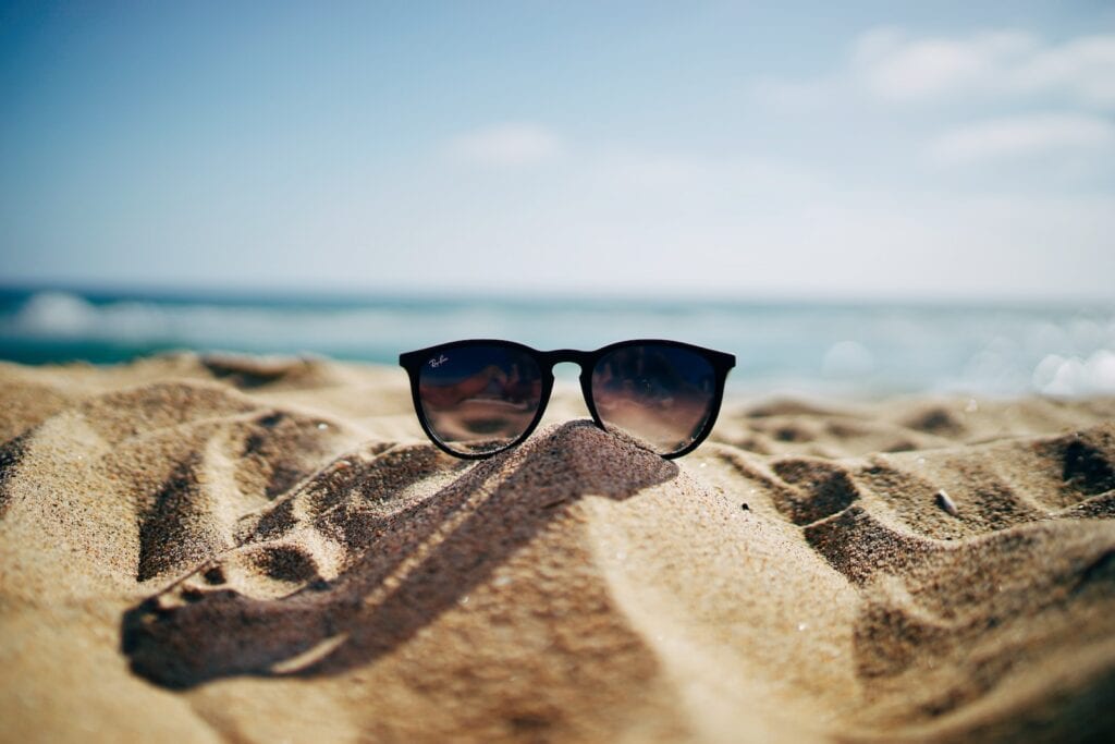 25 Pros and Cons of Living in New Hampshire in 2024 13 Black sunglasses on top of a small hill made of sand near the beach. New hampshire boasts many of the cleanest beaches in the country.