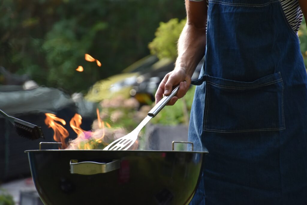 27 Pros and Cons of Living in Tennessee in 2024 10 A person wearing a denim apron grillling on the outdoors. The Tennessee BBQ is a famous cuisine in the state.