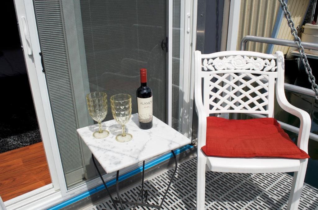 21 Best Places To Stay In Victoria, Canada 2024 13 A small square table with two wine glasses and a bottle of wine on top. A white chair can also be seen beside the table. This is A Float Home B&B in Victoria, Canada.