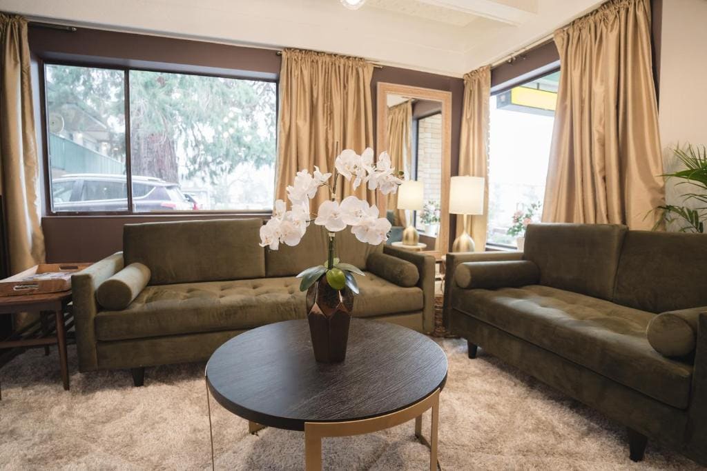 21 Best Places To Stay In Victoria, Canada 2024 20 A round table with a large flower vase on top near two dark green couches. This is in the Robin Hood Inn and Suites, Victoria