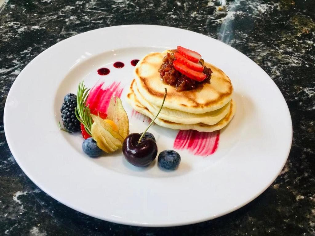 21 Best Places To Stay In Victoria, Canada 2024 21 a plate of pancakes with candies bacon, strawberries, a cherry, blackberries, a couple of blueberries, and some decorative food.