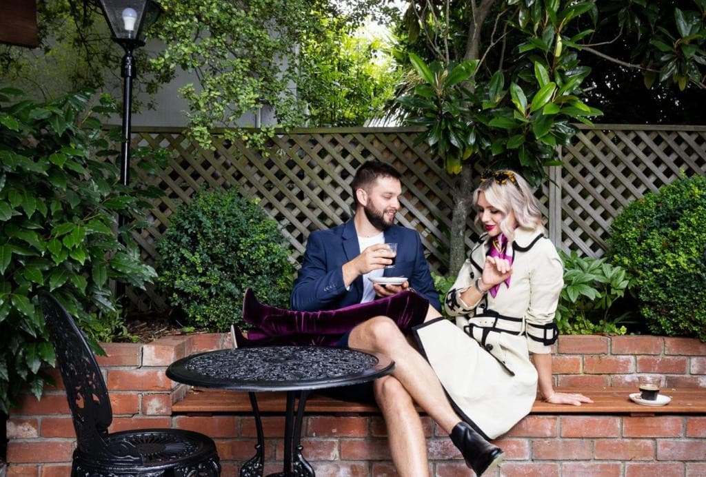 18 Best Hotels in Christchurch, New Zealand 2024 9 Two people talking to each other near a black circular table and chair. This is in Eliza's manor in Christchurch.
