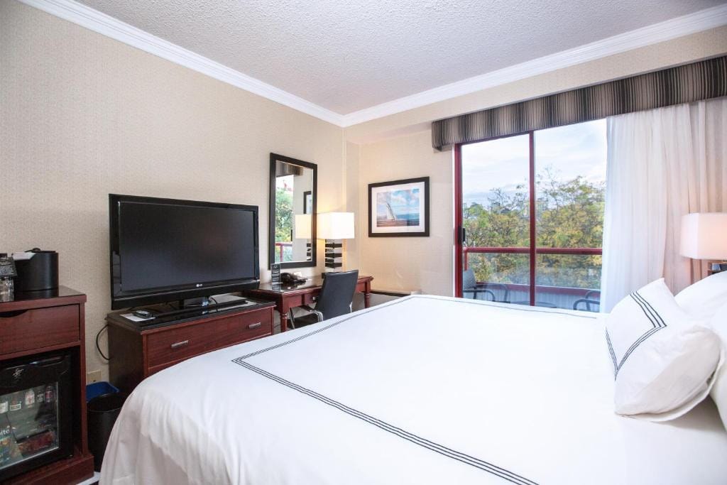 23 Best Vancouver Hotels with Balconies (A Local’s Guide) 13 A large bed in front of a dresser with a TV on top. Beside the bed is a sliding door towards a balcony. This is in the Granbille island Hotel, Vancouver