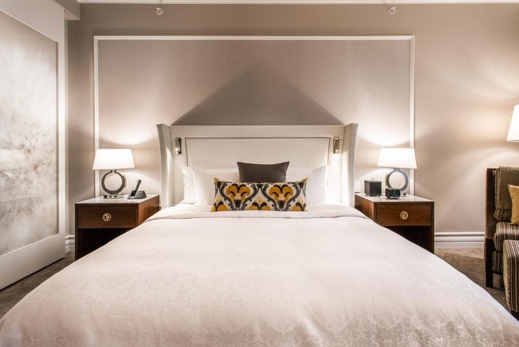 A hotel room with a bed with white sheets and bedside tables and lamps on both sides. This is in the Hotel Birks Montreal.