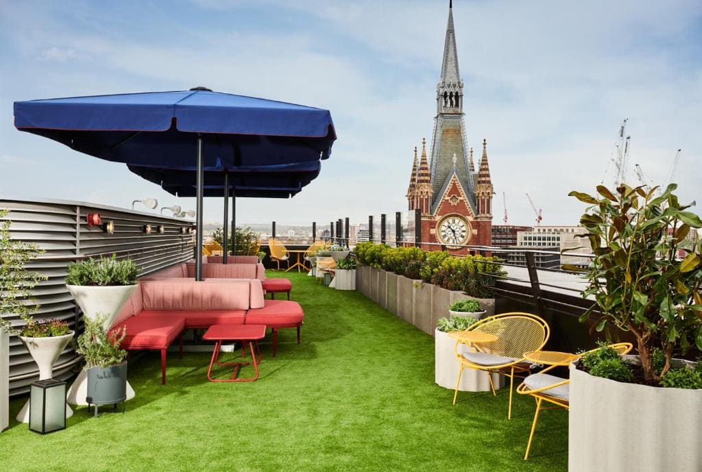 27 Best London Hotels with Balconies 2024 13 A rooftop terrace with chairs and umbrellas and a clock tower in the background. This is in the Standard, one of the best londol hotels with balconies.