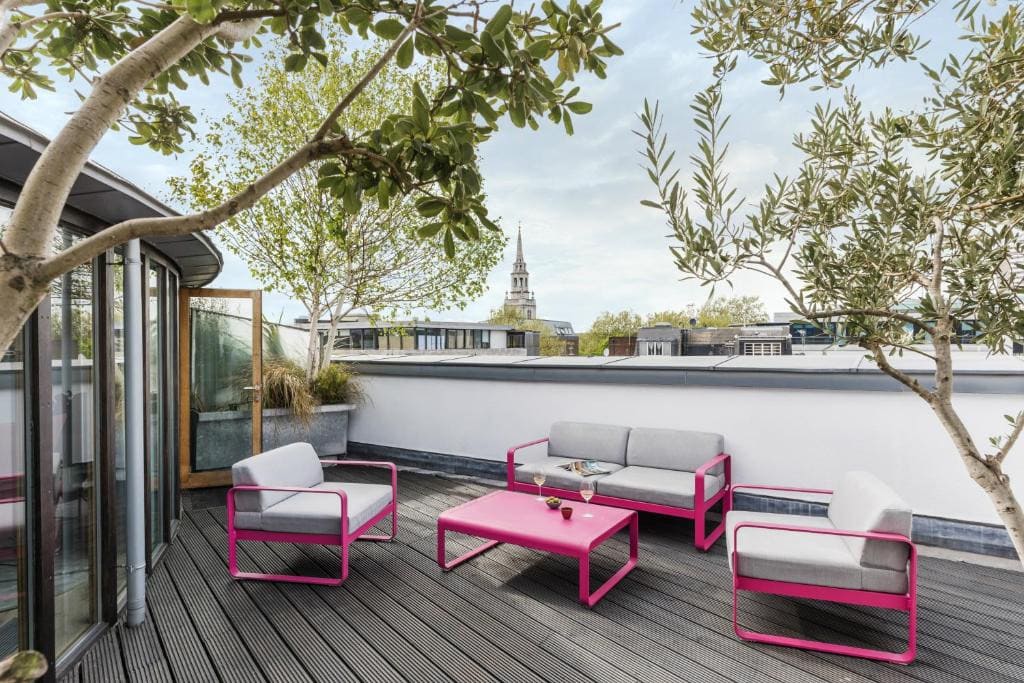 27 Best London Hotels with Balconies 2024 18 Pink furniture on a wooden deck with a view of the tower of london. This is in the Marrable.s Hotel, one of the best london hotels with balconies.