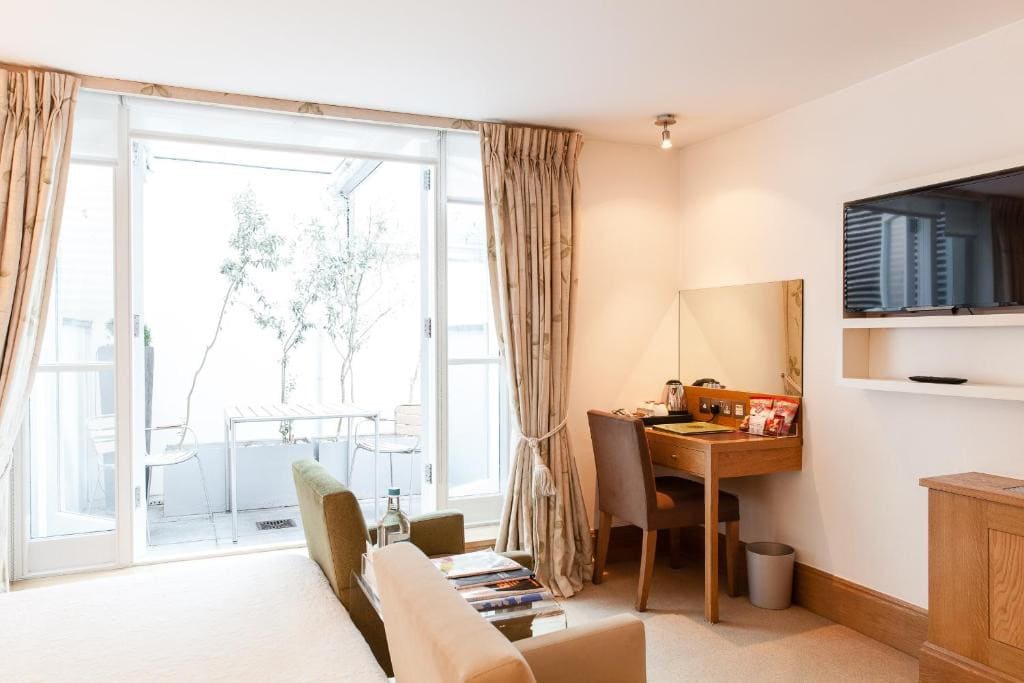 27 Best London Hotels with Balconies 2024 26 A room with a bed, desk and tv.