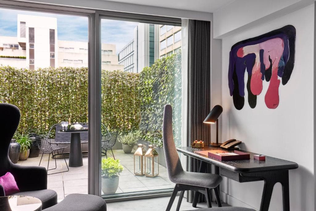 27 Best London Hotels with Balconies 2024 27 A hotel room with a desk and chairs, London hotels with balcony rooms.