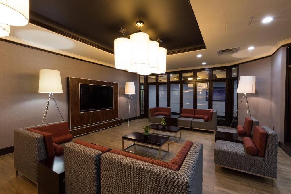 11 Best Edmonton Hotels With Balconies 2024 5 A couple couch sets placed in the middle of a room with linoleum flooring. The room has a chandelier, tall lamps, and a wall-mounted flat screen TV. This is in the Holiday Inn Express Edmonton Downtown