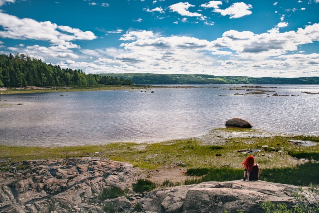 21 Best Day Trips From Quebec City 2025 8 A large lake near trees and grass. Different sized of rocks can also be seen in the photo. This is in the Saguenay Fjord national Park.