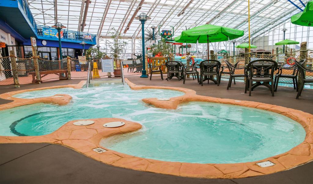15 Luxurious Niagara Falls Resorts (2024 Guide) 9 bubbling jacuzi with black chairs and tables with green umbrellas and a lamp post at Americana Conference Resort Spa & Waterpark