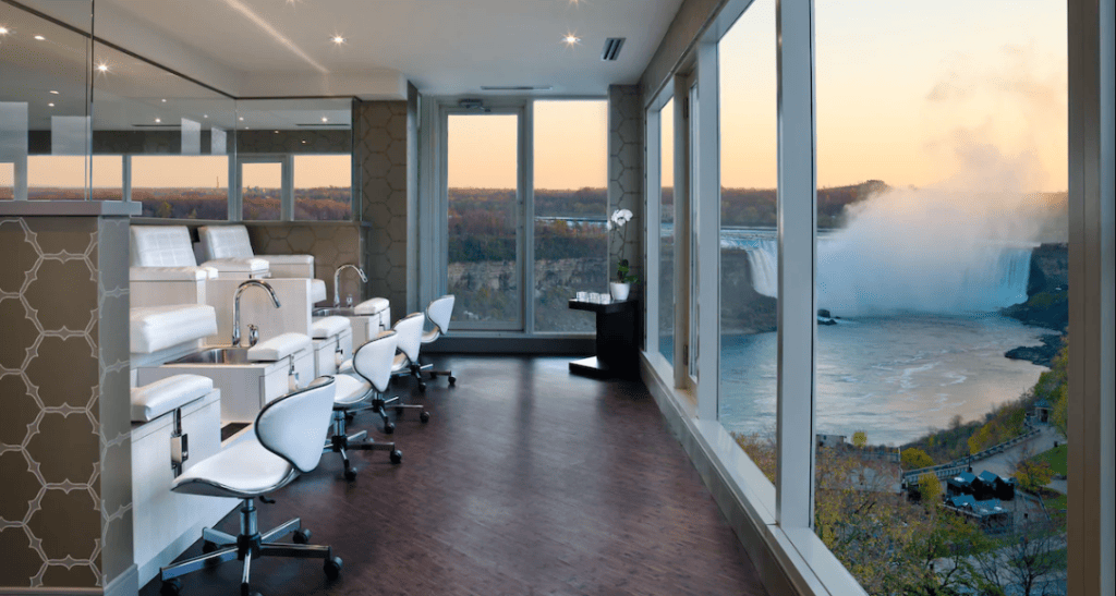15 Luxurious Niagara Falls Resorts (2024 Guide) 18 white spa chairs in room with corner windows with view of niagara falls at Crowne Plaza Niagara Falls Fallsview