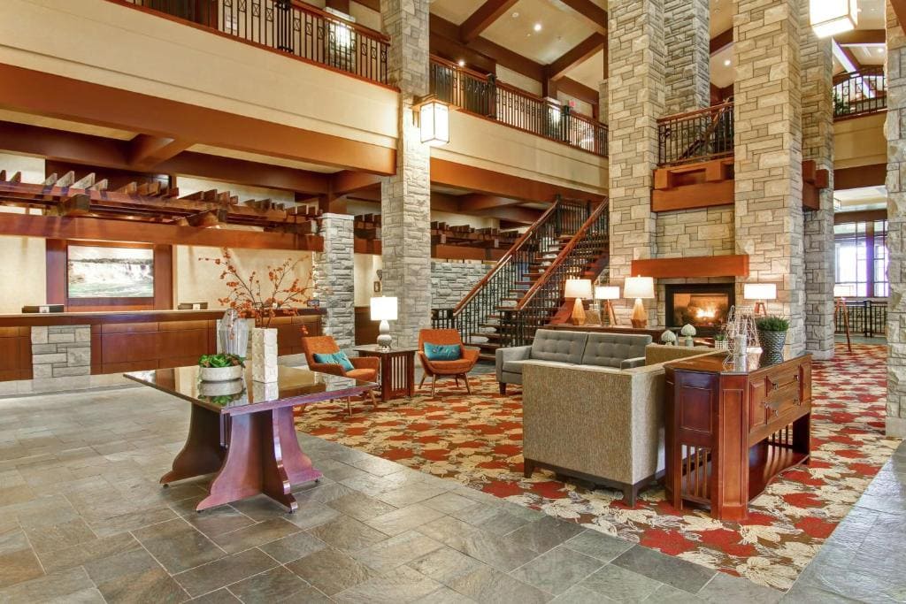 15 Luxurious Niagara Falls Resorts (2024 Guide) 7 inside DoubleTree Fallsview Resort & Spa beautiful interior inside the lobby. With huge sitting area and a staircase leading to the rooms. the lobby has lamps, huge brick pillars and a fire place.