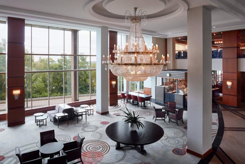 15 Luxurious Niagara Falls Resorts (2024 Guide) 10 Inside Marriott Fallsview Hotel and Spa lobby with sitting and dining areas. A huge gold chandelier hangs on the ceiling. A huge window gives a view of the trees outside