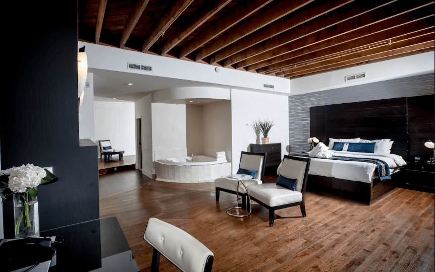 15 Luxurious Niagara Falls Resorts (2024 Guide) 13 huge suite bedroom with king bed and indoor tub and lounge chairs and wood ceiling and flooring