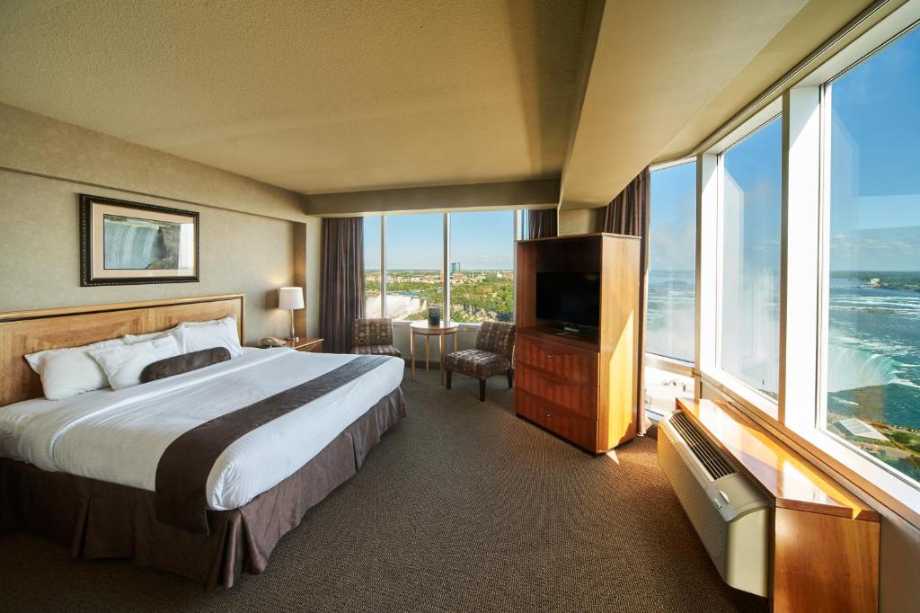15 Luxurious Niagara Falls Resorts (2024 Guide) 19 corner bedroom at The Oakes Hotel Overlooking the Falls with king bed and television and airconditioning. the room has wide windows and has and outside view of the niagara falls.