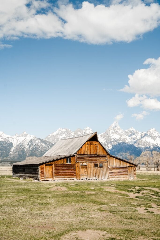23 Pros and Cons of Living in Wyoming (2024) 6 brown wooden barn near snow covered mountain under blue sky during daytime in Wyoming