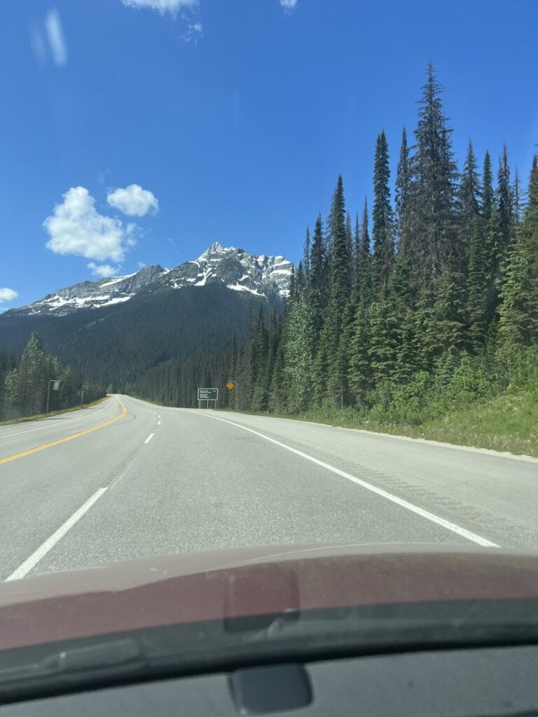 83 Bucket List Canada Things to Do in 2025 from a Canadian 1 Scenic drive through the Canadian Rockies with a clear view of majestic mountains ahead, depicting the natural beauty of Canada's driving routes.