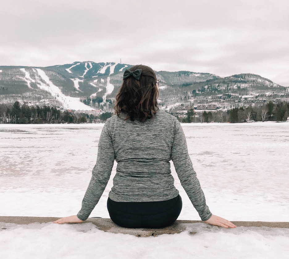 Canada's Top Winter Sports Destinations: A Guide for Thrill Seekers 5 A girl with short curly hair wearing a ribbon sitting on the edge while facing the mountain covered in snow at Blue Mountain, Ontario, Canada's Top Winter Sports Destination.