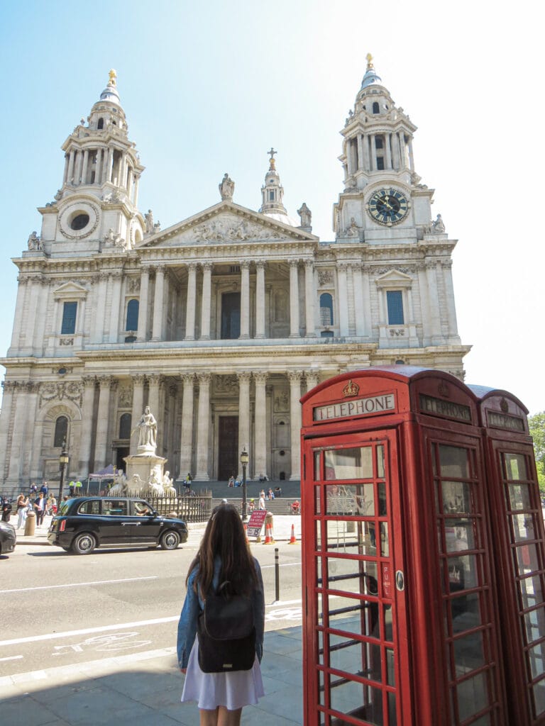 Discover Life Beyond the Tourist Trails in Spain's Coastal Towns Through a Local's Eyes 3 Back view of a woman observing St. Paul's Cathedral next to an iconic red telephone box in the UK, a contrast to Cristina's life in Costa Del Sol.