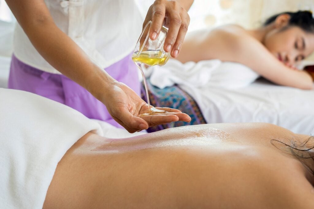 9 Best Spas in Quebec City For Ultimate Relaxation 2 woman lying with prone position with a masseuse pouring oil on her back for a massage.