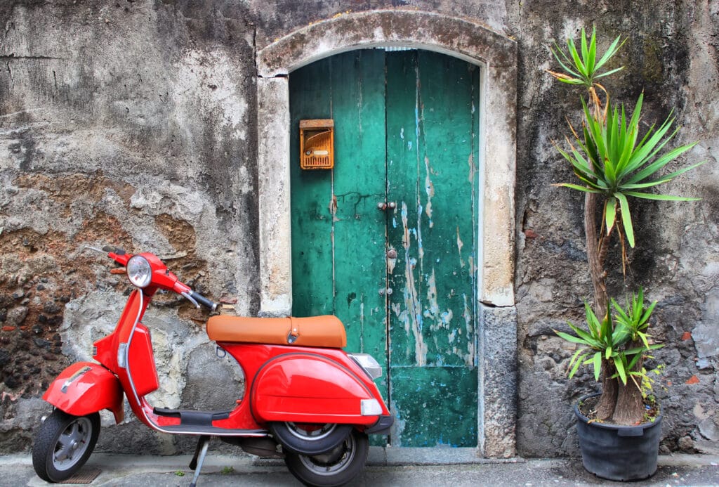 Things I Took For Granted Until I Moved to Italy 6 Photo of red scooter near green door and palm tree in Italy.