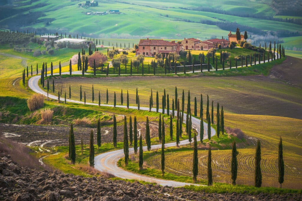 Things I Took For Granted Until I Moved to Italy 5 Winding dirt road through farmland in Italy towards a farmhouse.