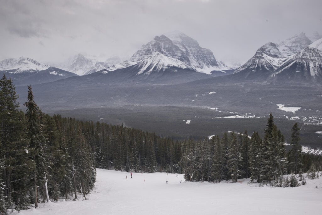 Canada's Top Winter Sports Destinations: A Guide for Thrill Seekers 3 People skiing down at Banff National Park overlooking the mountains.