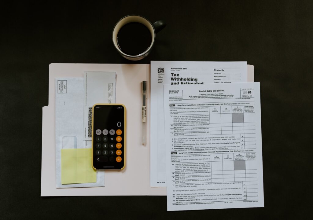 Cost of Living in Canada vs US (Complete 2024 Comparison) 7 A smartphone on the calculator application beside tax forms.