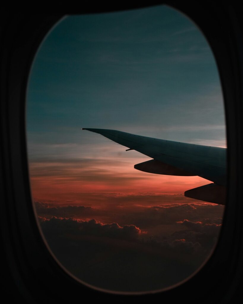 20 Reasons Not to Live in the US (2024) 19 A view of the aiplane wings through the passenger window while flying over the clouds during dawn.