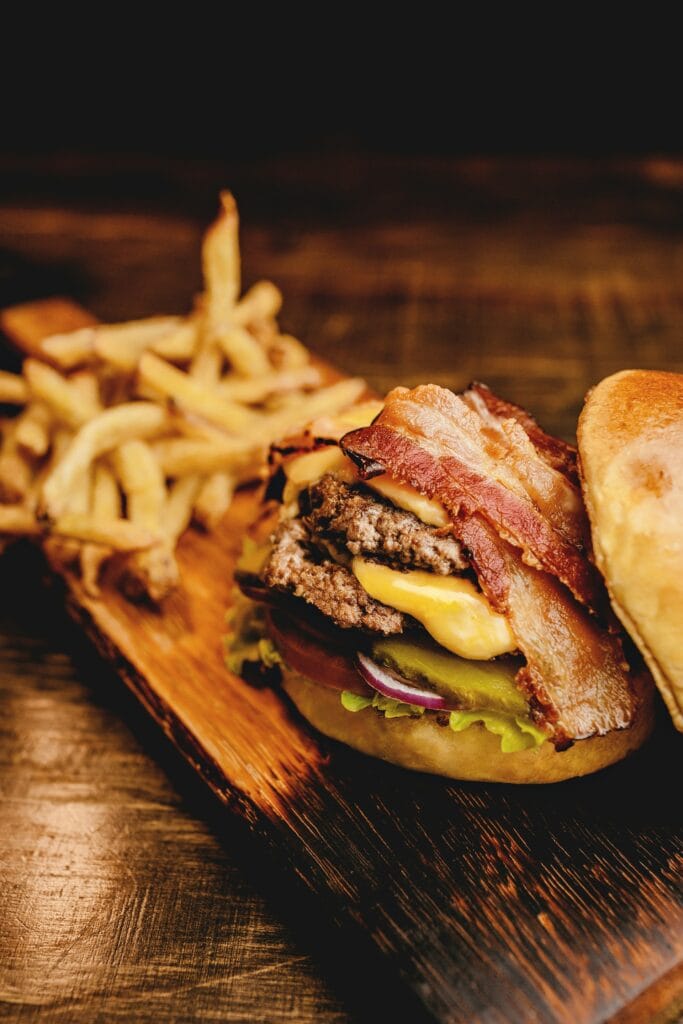 20 Reasons Not to Live in the US (2024) 13 A hamburger with bacon and double beef patty with fries on the side.