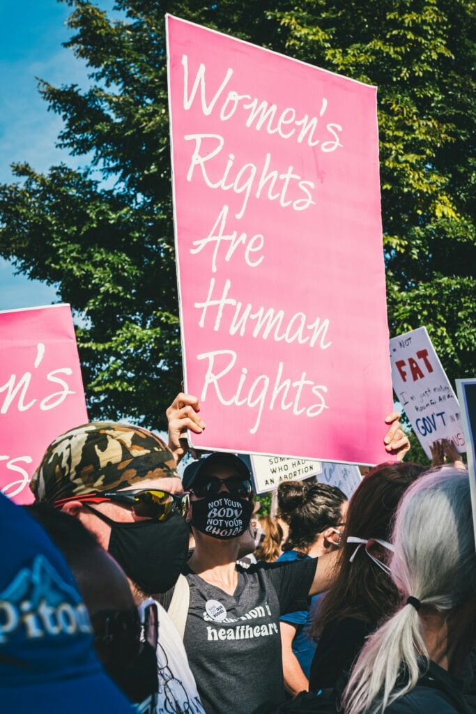 20 Reasons Not to Live in the US (2024) 4 A crowd holding pink signage rallying for women's rights.