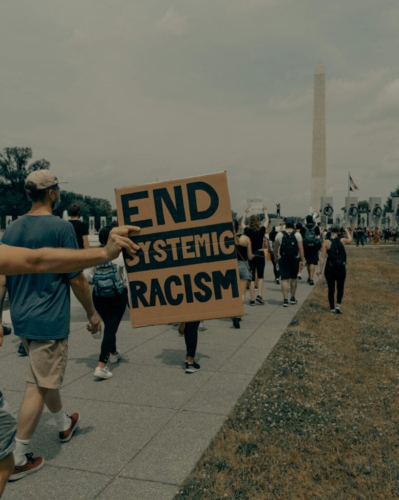 20 Reasons Not to Live in the US (2024) 11 A crowd march towards Washington monument holding signages to end racism.