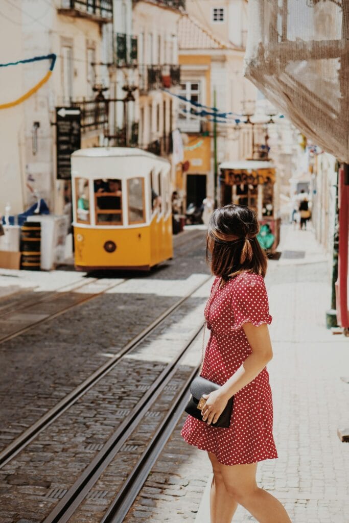 14 Top Freelance Visa Countries To Live And Work In 2024 2 A woman wearing a red pola dot dress with black bag walking by the rail of the electric trains.