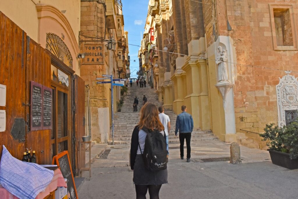 ALL European Countries With Digital Nomad Visas (2024) 14 A woman with black backpack wwalking ont the streets of Malta.