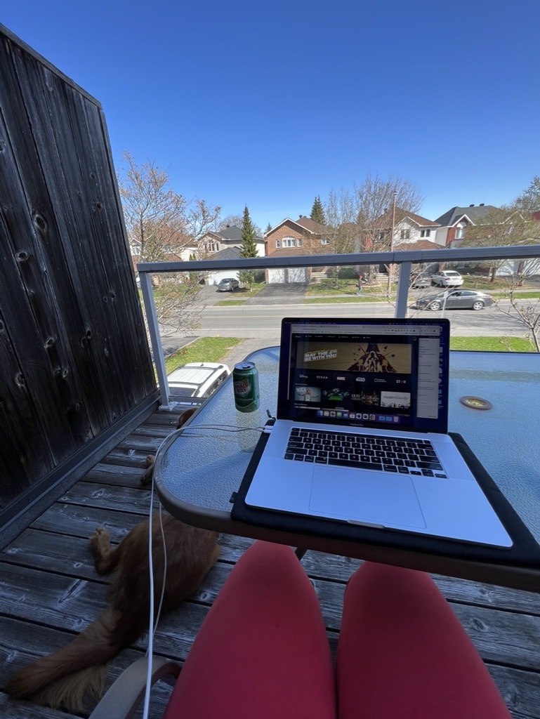 35 Pros and Cons of Living in the UK in 2024 6 An open laptop on a table on a balcony in a quiet residential neighborhood.